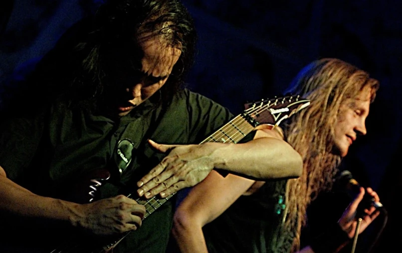 two men one with long hair playing guitar