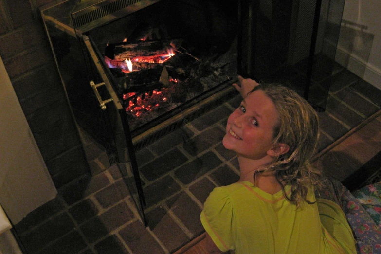 a young lady sitting in front of an oven smiling