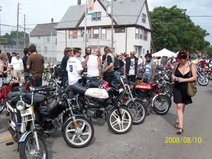 many people gather around parked motorcycles and looking at the show