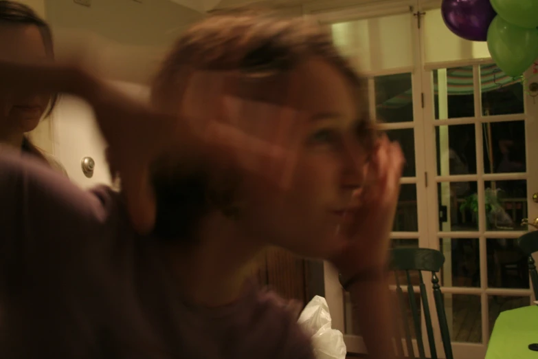 a woman is making her face with balloons hanging up in the background