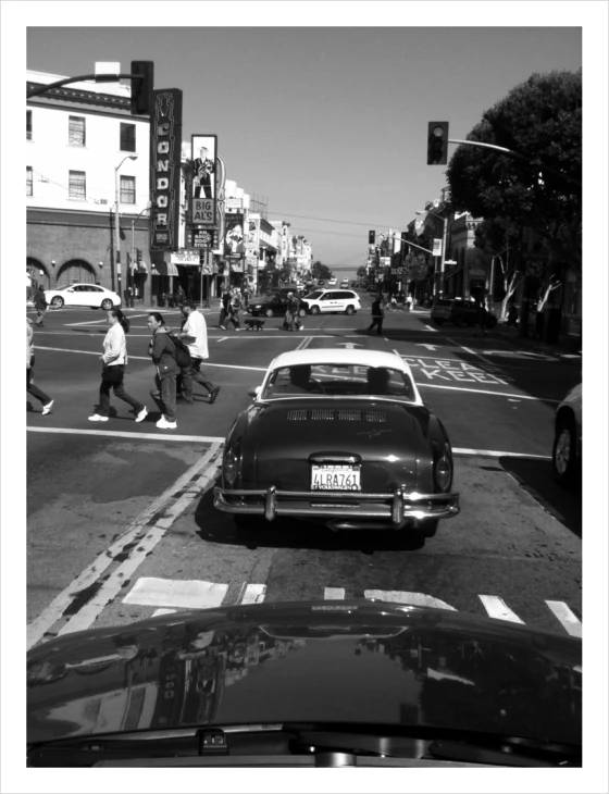 a car driving down a city street next to a pedestrian cross walk