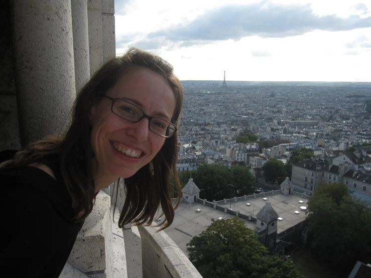 a woman wearing glasses in front of an overview of a city