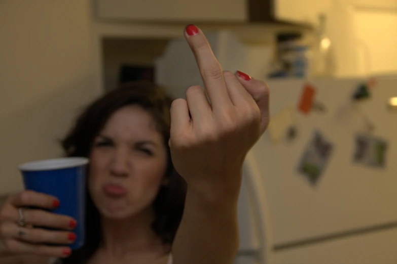 woman making funny face while holding up a blue cup