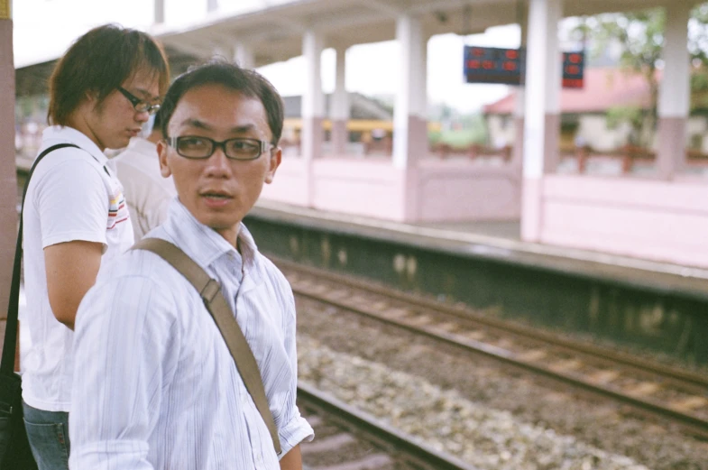 two asian males in front of a train station