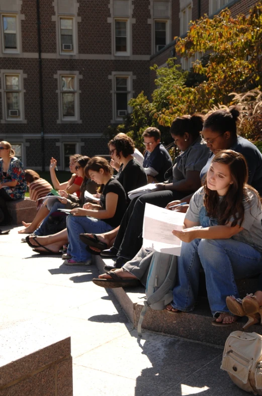 a crowd of people sitting down on the stairs outside a building