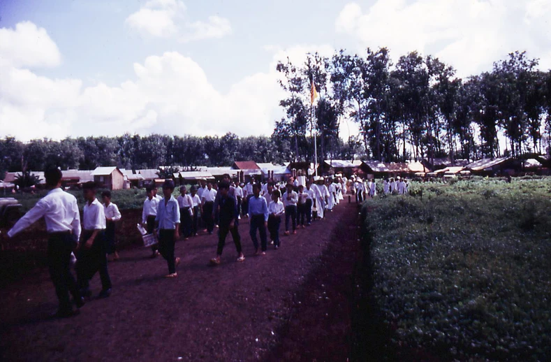 a group of people wearing white shirts are walking along the road