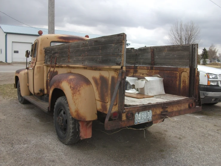 an old rusty truck is parked in a parking lot