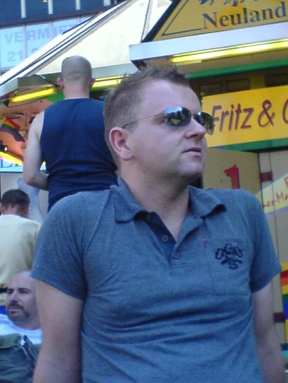 man in glasses stands in front of a food stand