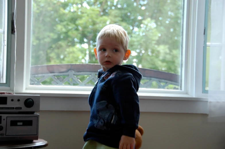 a little boy sitting in a chair next to a window