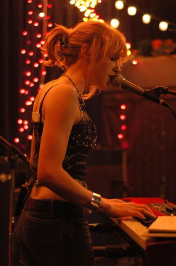 a woman at a keyboard sings into a microphone