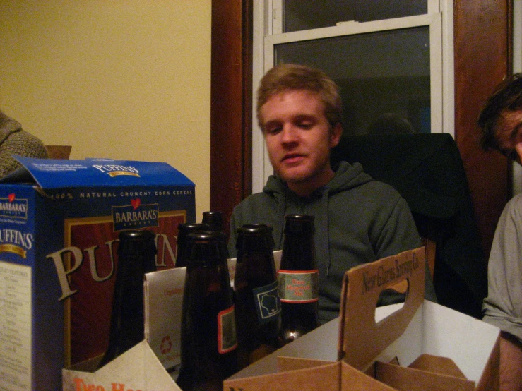 two men sitting near a box with some beer