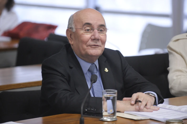 a man in suit sitting down and having his hands over a piece of paper