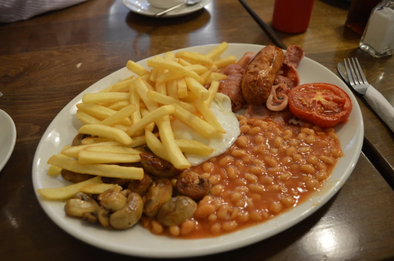 a white plate topped with beans, potatoes and meat