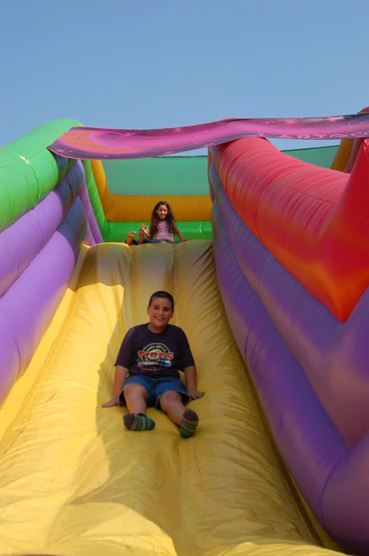 the boy is sitting in a colorful bounce castle