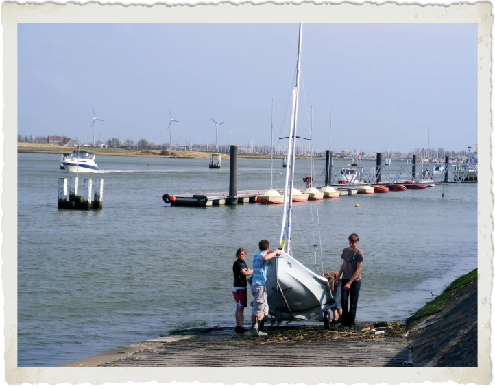 several children and one adult are standing on a dock by a sail boat