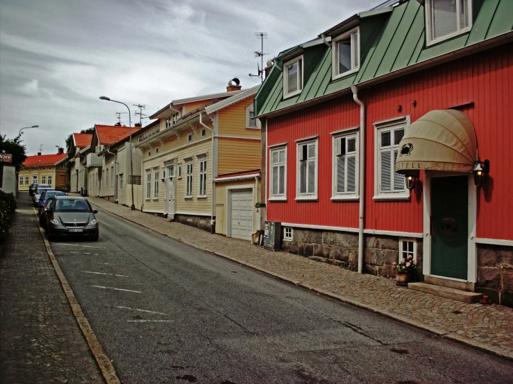 cars and buildings on the side of a street in front of red wall