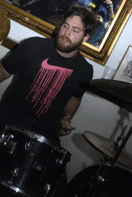 man in black t - shirt playing drums while smiling