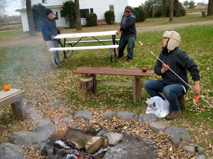 people on a campfire preparing food with tongs