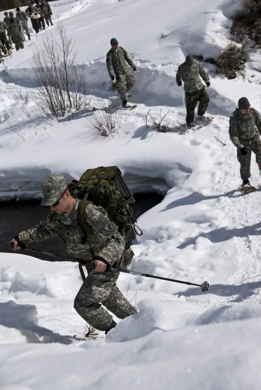 many soldiers moving through the snow, one soldier wearing skis