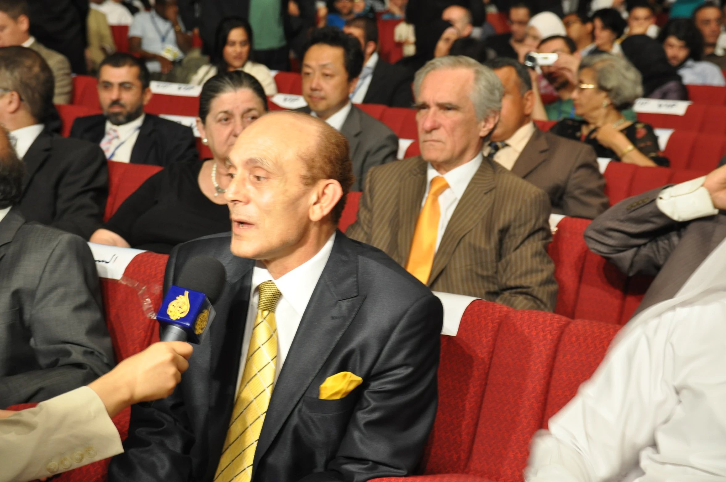 many people are wearing business suits in a lecture hall