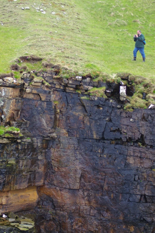 a man in a field next to some cliffs