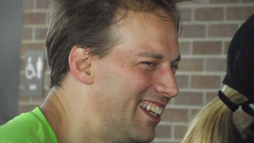 man with blonde hair smiling next to a woman