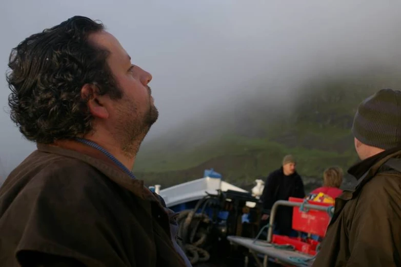 two men standing in front of tents on top of a hillside