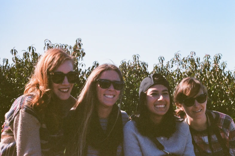 three girls pose for a picture with a sky background