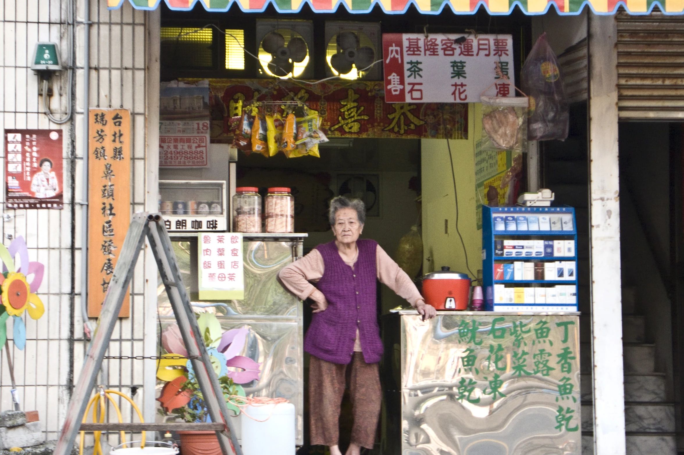 an older woman stands outside a store selling goods