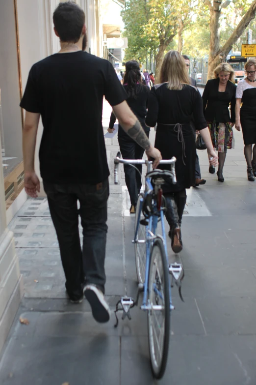 a man walking with a tattoo holding onto a bike