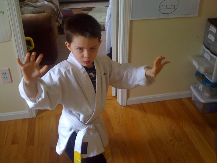 a small boy wearing karate garb and getting ready to kick a yellow kick