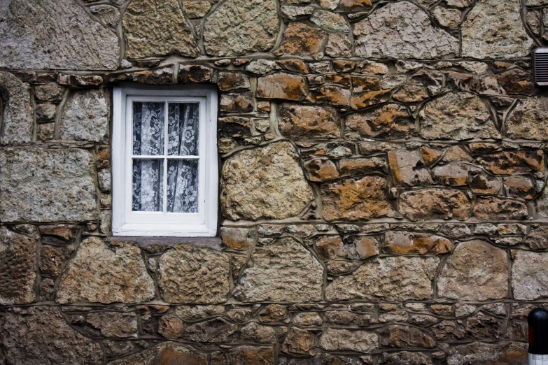 a stone building with white window frame and a red fire hydrant