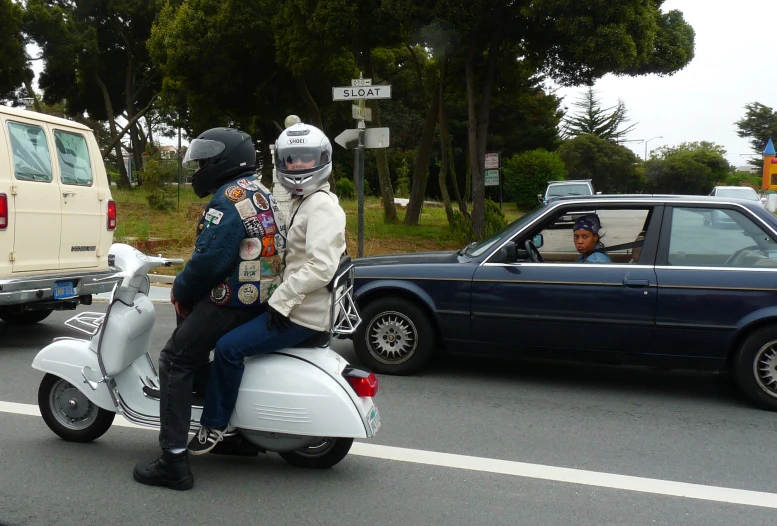 there are two people riding a scooter on a busy street