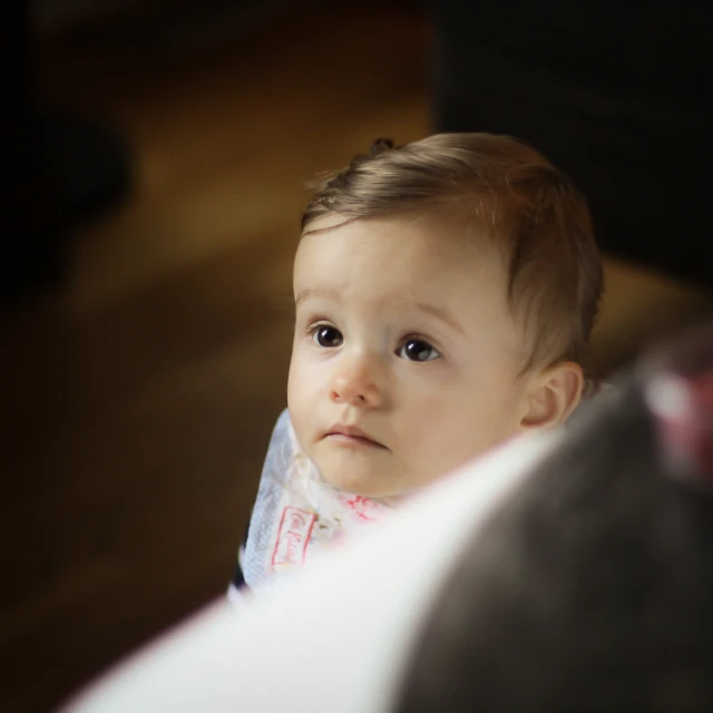 a baby looking at the camera while standing up