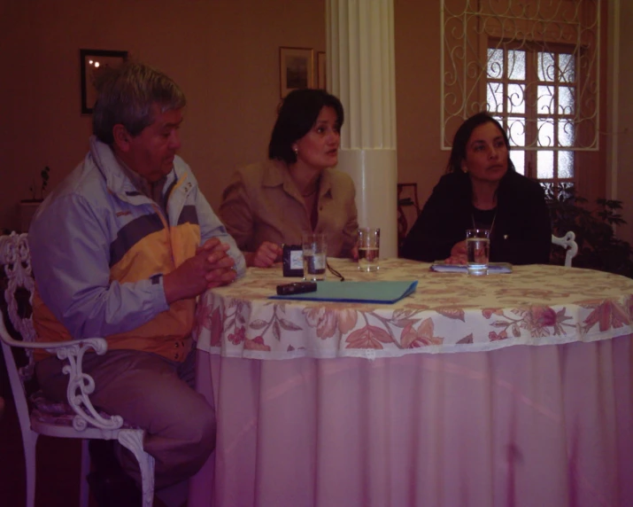 three people sit around a table drinking water and chatting