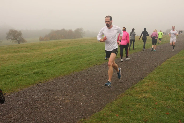 a group of people run on a path in the fog