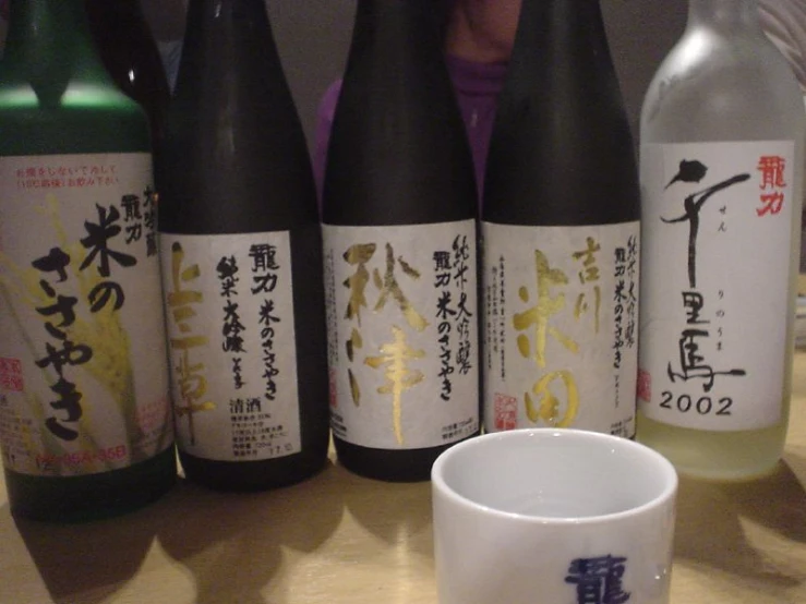 a table topped with a cup and bottles of alcohol