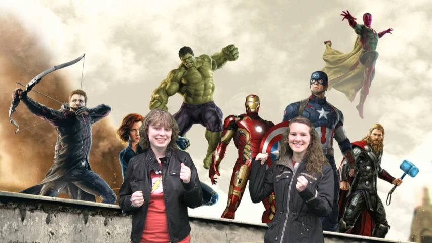 two women standing in front of a po of the avengers