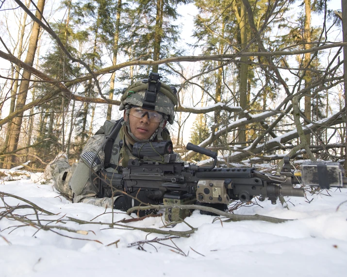 a man wearing camouflage kneeling in the snow with a gun