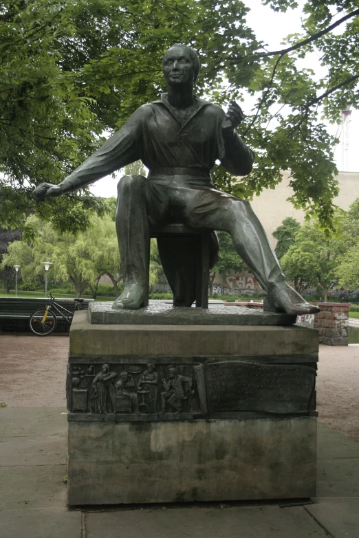 a statue of a man is sitting on the side walk
