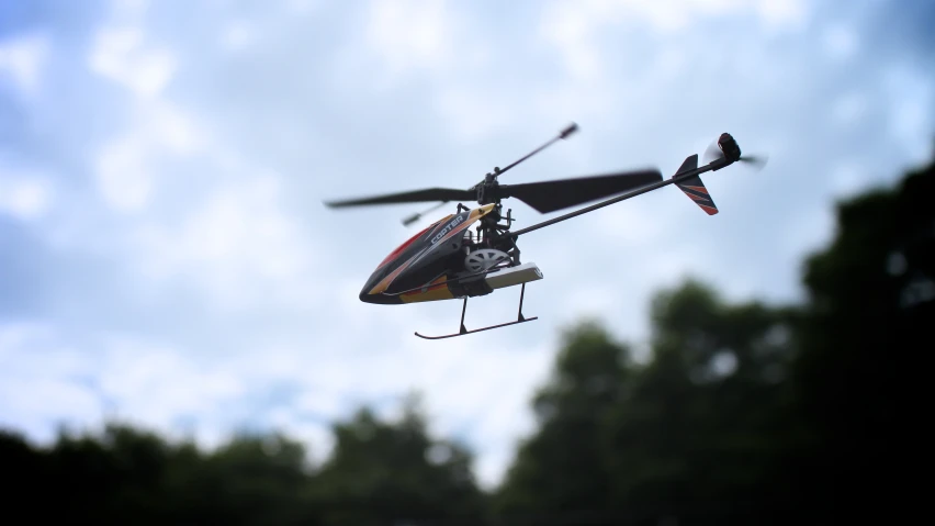 a small red helicopter flying thru a sky