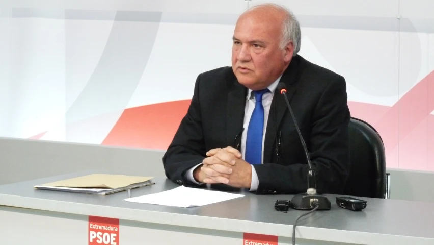 a man in a suit and tie is sitting at a podium