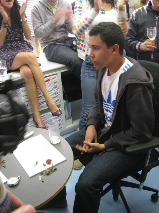 two people sitting on chairs in front of a man on the phone