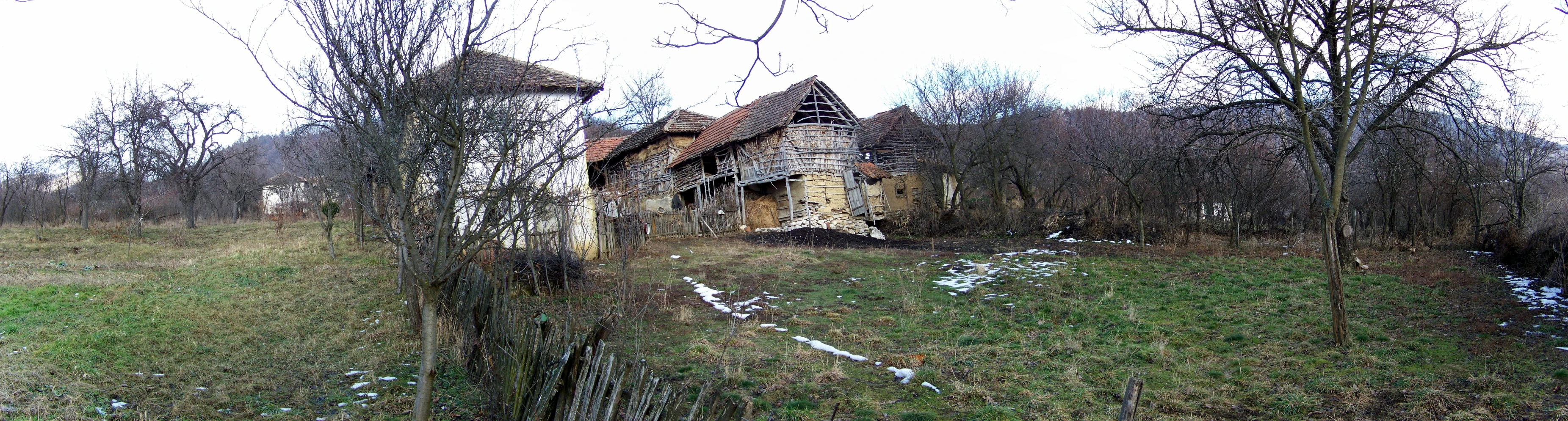 an abandoned building sits in the middle of a tree filled field