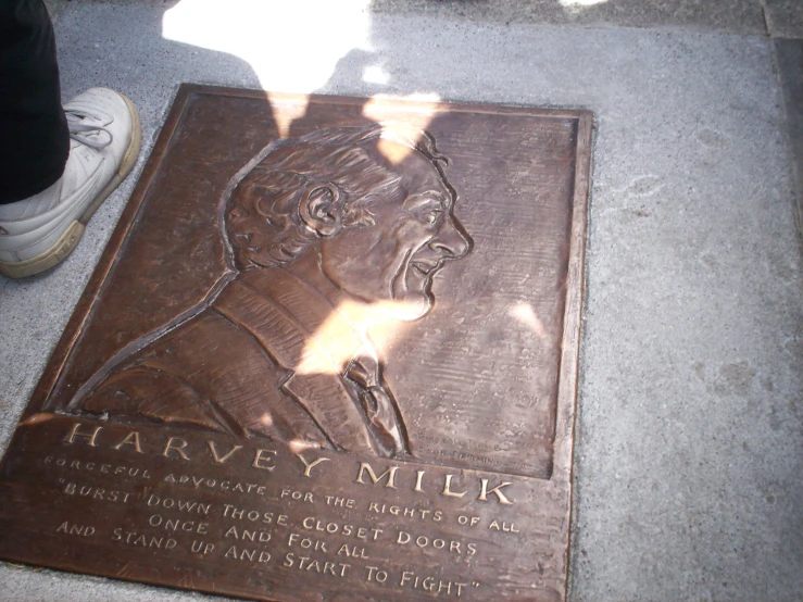 a plaque showing a man's profile on the sidewalk