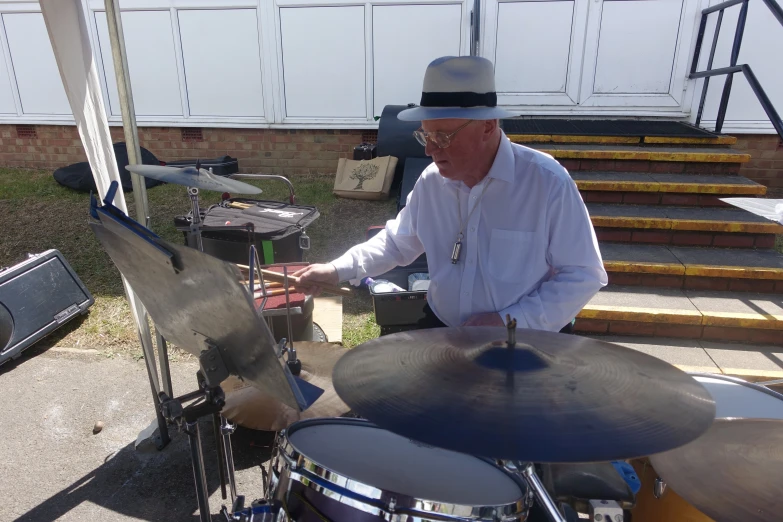 man playing drums on some steps in a back yard