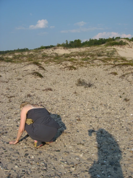 a person kneeling on a beach looking at soing
