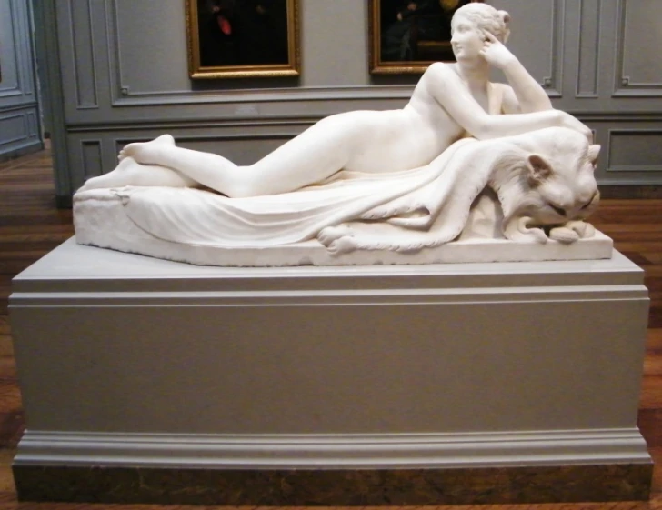 a white statue with a woman lying on the back of it