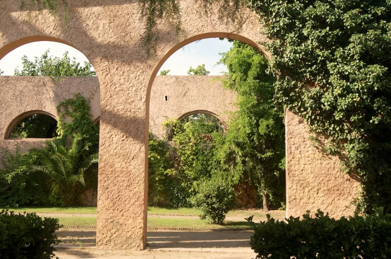 an outside view of a stone building, with three arches and small plants