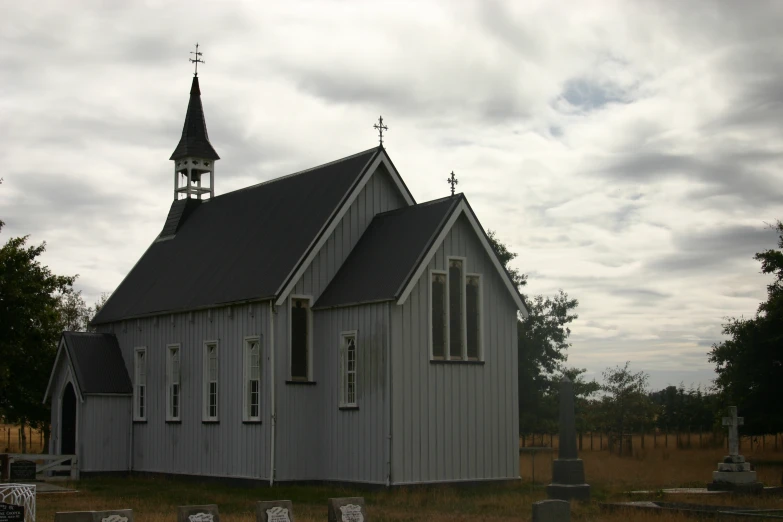 an old church with a steeple sits in an empty cemetery